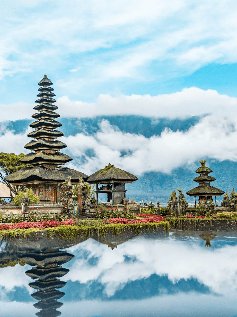 Intricate Balinese temple with mountain views and cloud reflections in a serene landscape.
