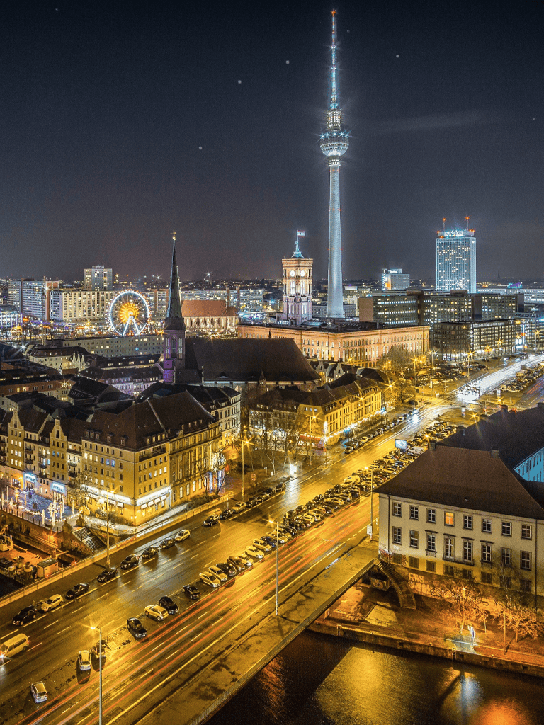 Bright night skyline of Berlin with TV Tower and illuminated streets, showcasing top travel destinations and city landmarks.