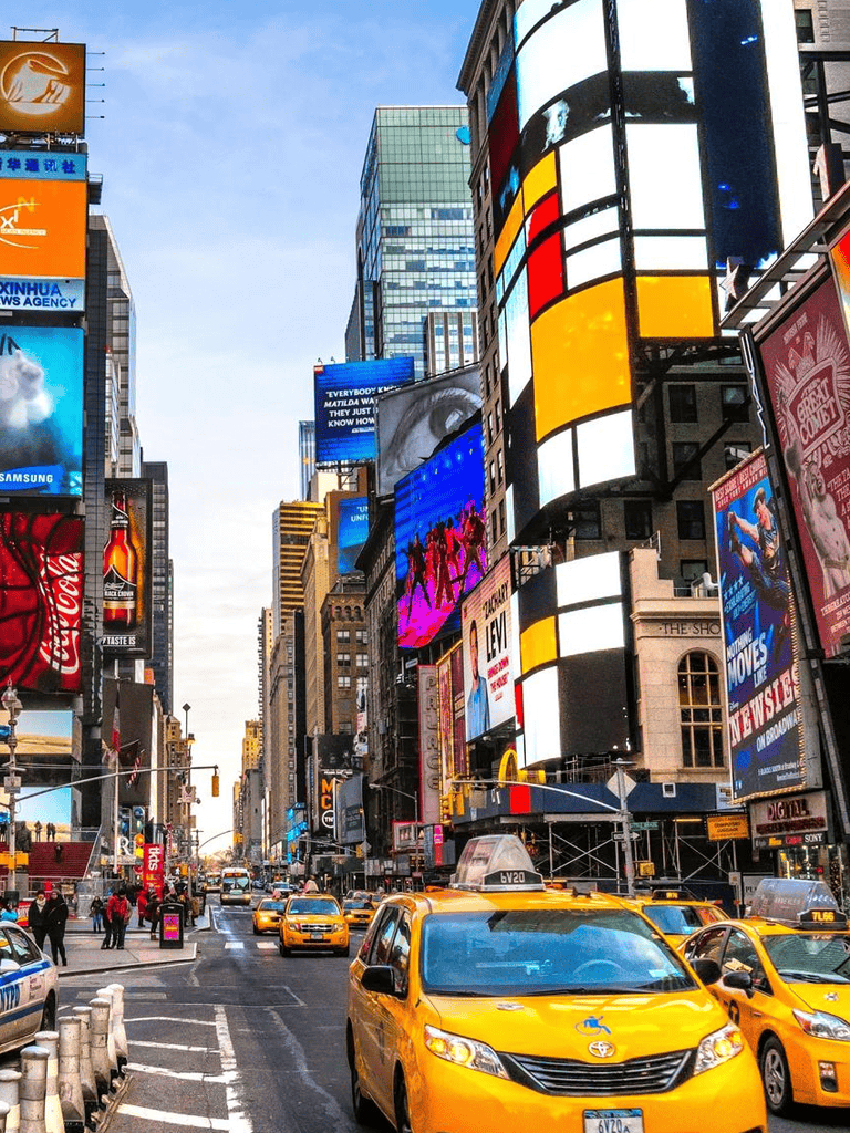 Yellow taxis in Times Square, New York City with vibrant billboards and bustling crowds, showcasing iconic urban scenery.
