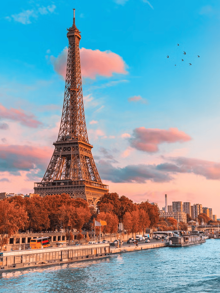 Eiffel Tower in Paris with sunset sky and River Seine in foreground.