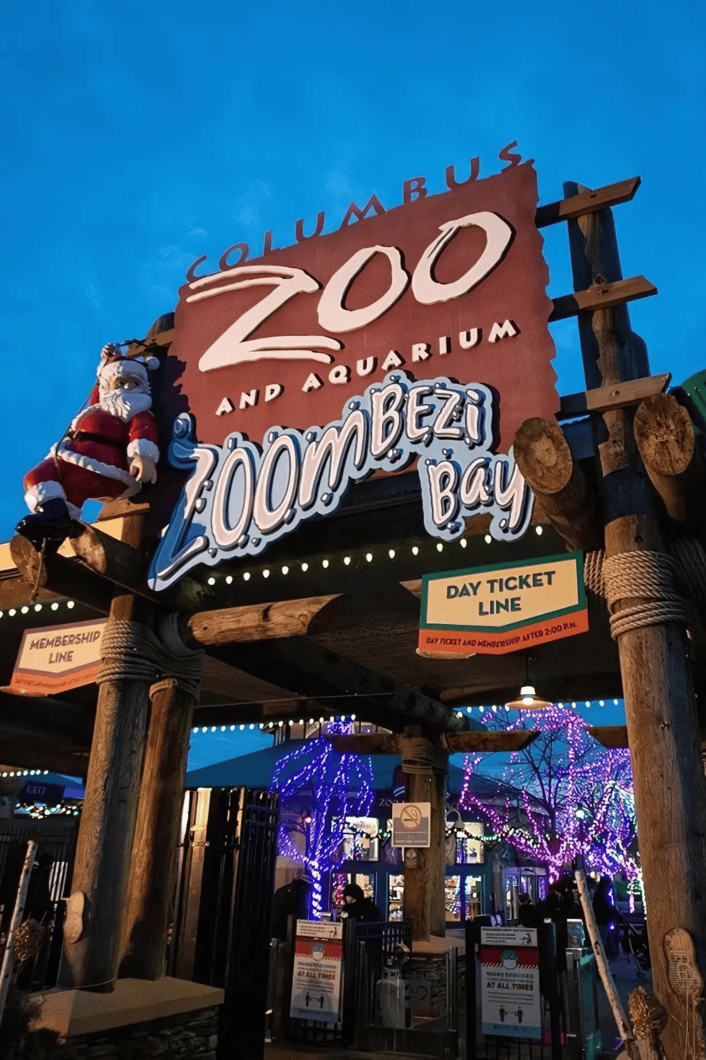 Zoo and aquarium entrance sign at Zoomba Bay, illuminated with festive lights, inviting visitors to explore wildlife and marine life exhibits.