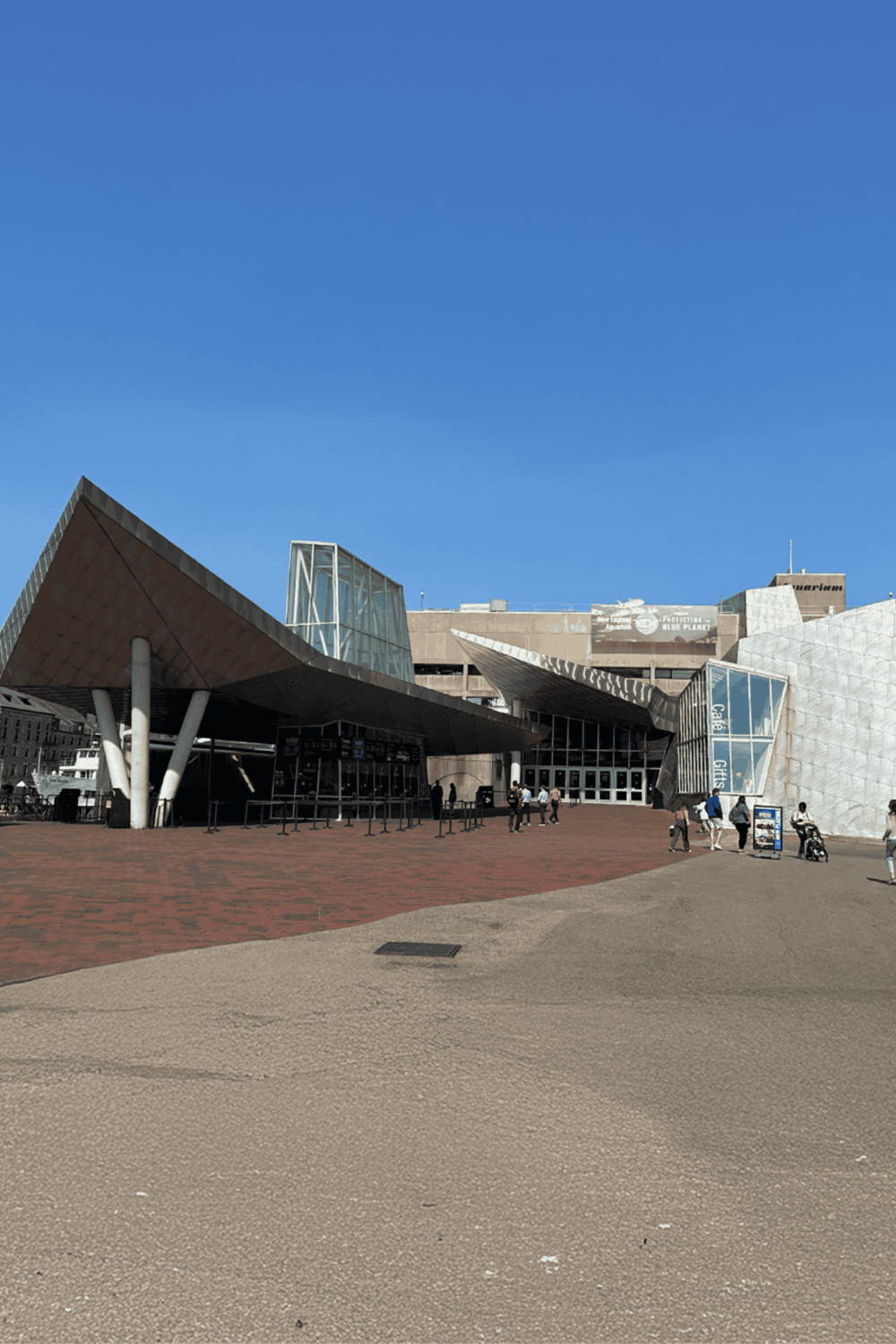 Modern museum building with striking architectural design, glass structures, and visitors outside.