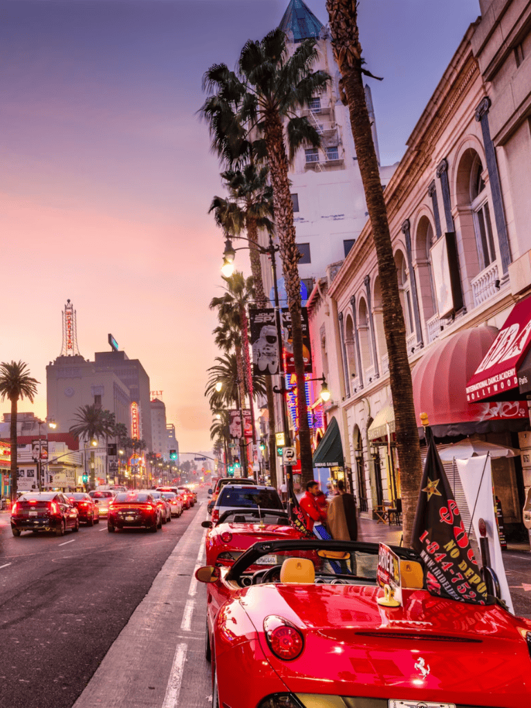 Vibrant sunset view of Hollywood Boulevard with palm trees, classic cars, and bustling nightlife, showcasing QuestForDirections location.