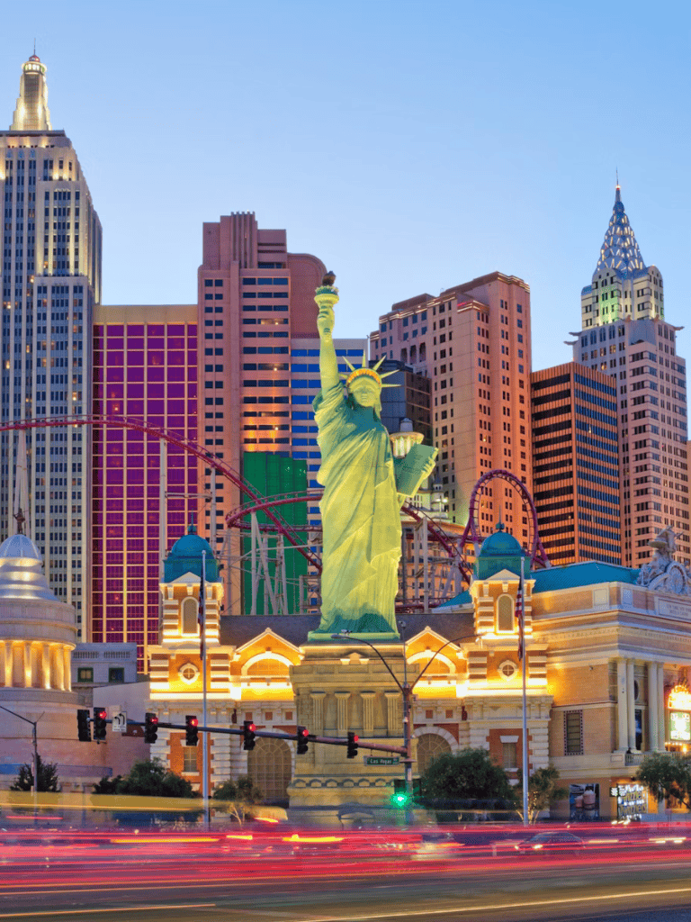 Iconic Las Vegas Strip with replica Statue of Liberty and vibrant city skyline at dusk.
