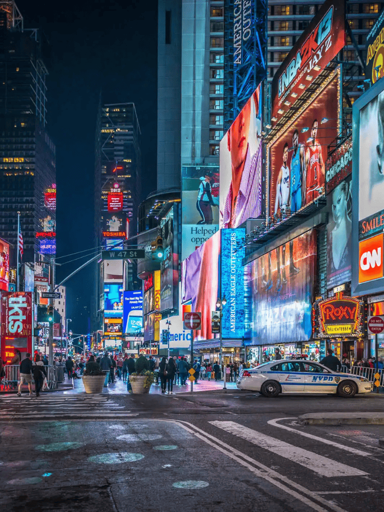 Bright Times Square at night with digital billboards and bustling pedestrians in NYC.