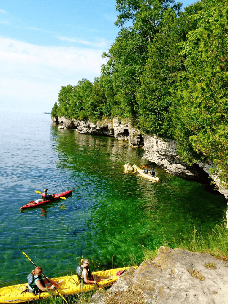 Kayakers exploring lush green cliffs along clear river waters for outdoor adventure.