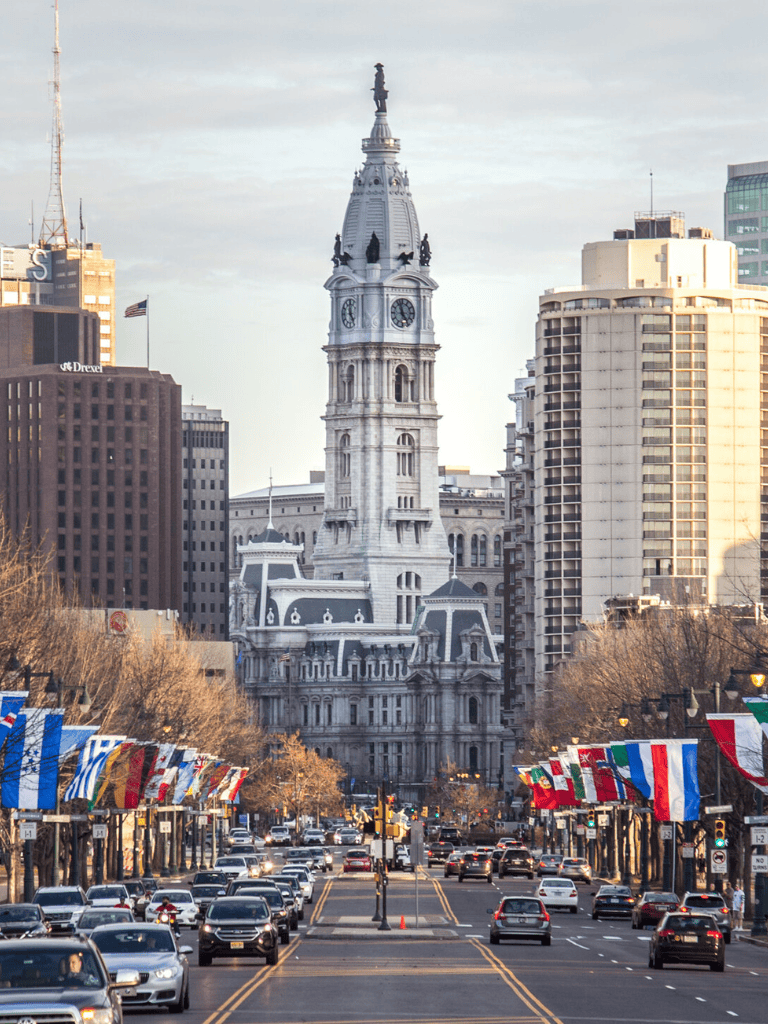 Philadelphia City Hall with flags and busy street scene.