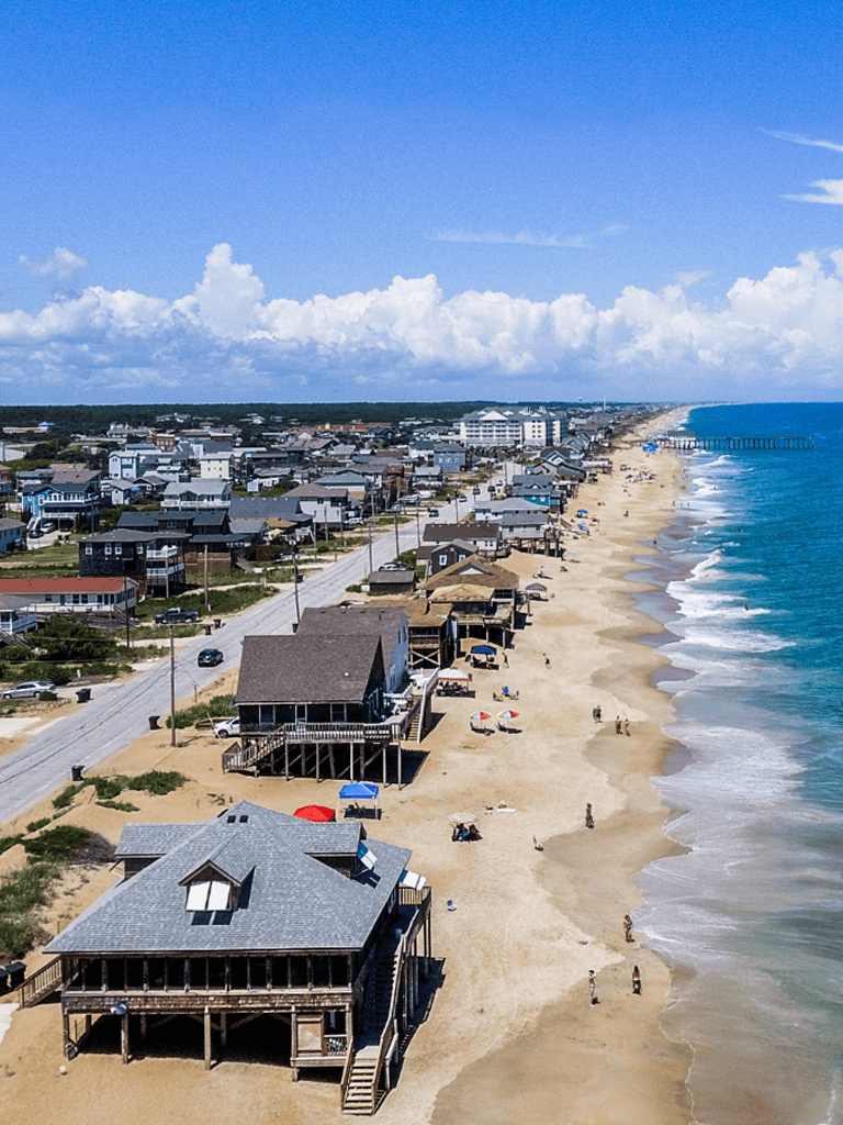 Stunning coastal beach homes and ocean view in a seaside town with pier in the distance.