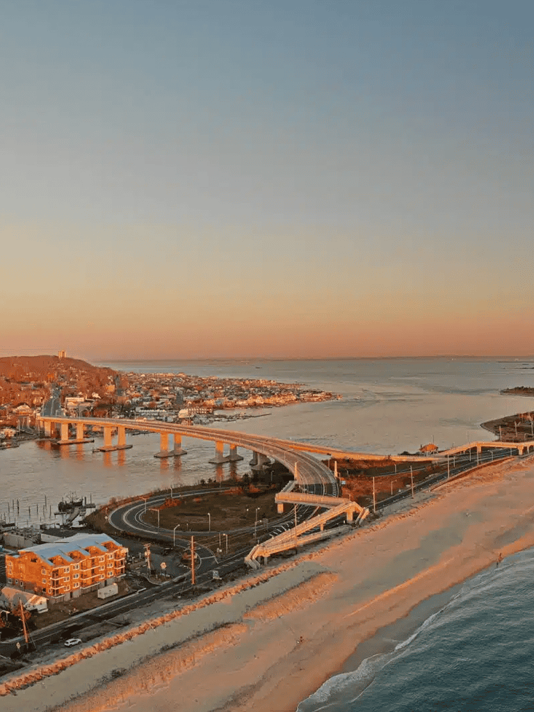Scenic coastal view with bridge and cityscape during sunset, promoting travel and navigation.