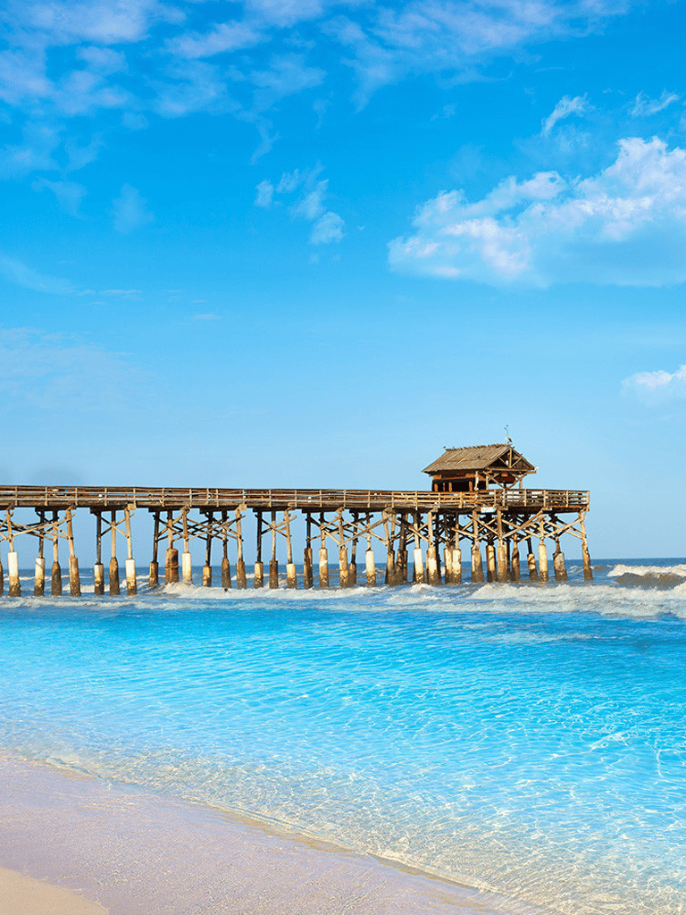 Pier over turquoise ocean with clear sky, perfect for beach travel and seaside adventures.
