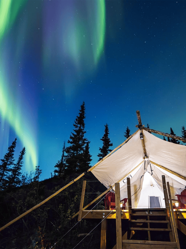 Northern Lights over cozy outdoor tent at Quest For Directions, adventure travel destination.
