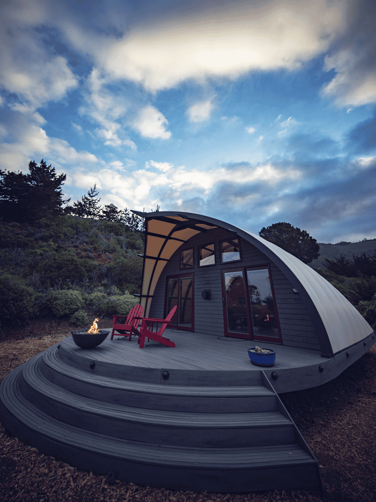 Cozy modern tiny house with curved design on outdoor deck in nature.