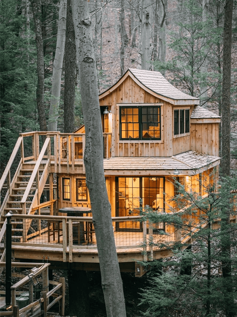 Cozy wooden treehouse in the forest with large windows and outdoor deck, perfect for nature retreat.