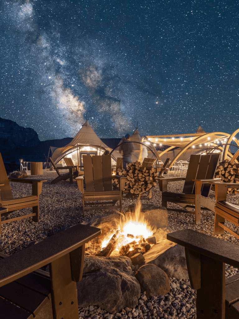 Starry night sky over outdoor fire pit and cozy campsite tents at QuestForDirections.