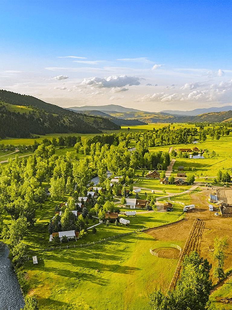 Idyllic rural landscape with rolling green hills and a small community of houses and farm buildings.