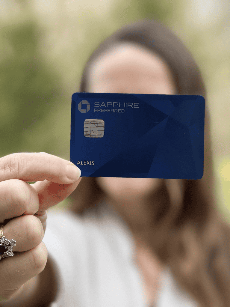 Sapphire preferred credit card held by woman, acrylic background.