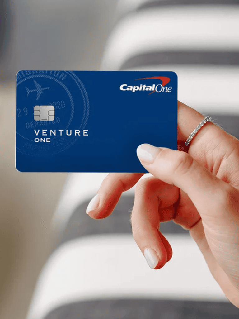 Blue Capital One Venture One credit card held by a hand.