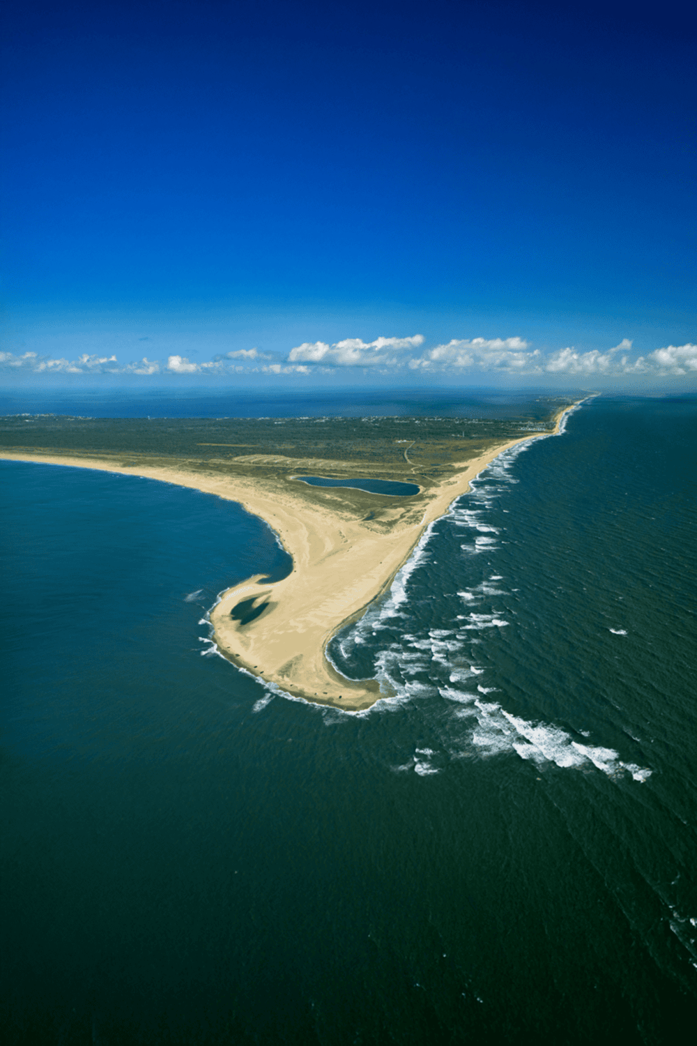 Aerial view of a coastal landform with sandy beaches and clear blue ocean, Sunny weather, distinctive peninsula shape, Adventure and travel destination.