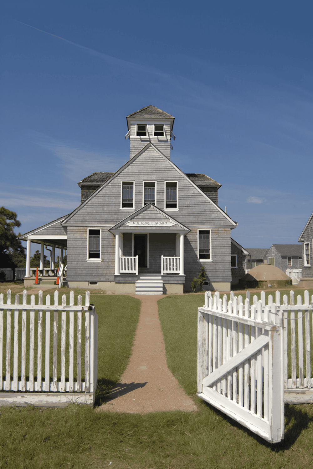 Rustic coastal lighthouse with classic architecture, white picket fence, and scenic ocean views.