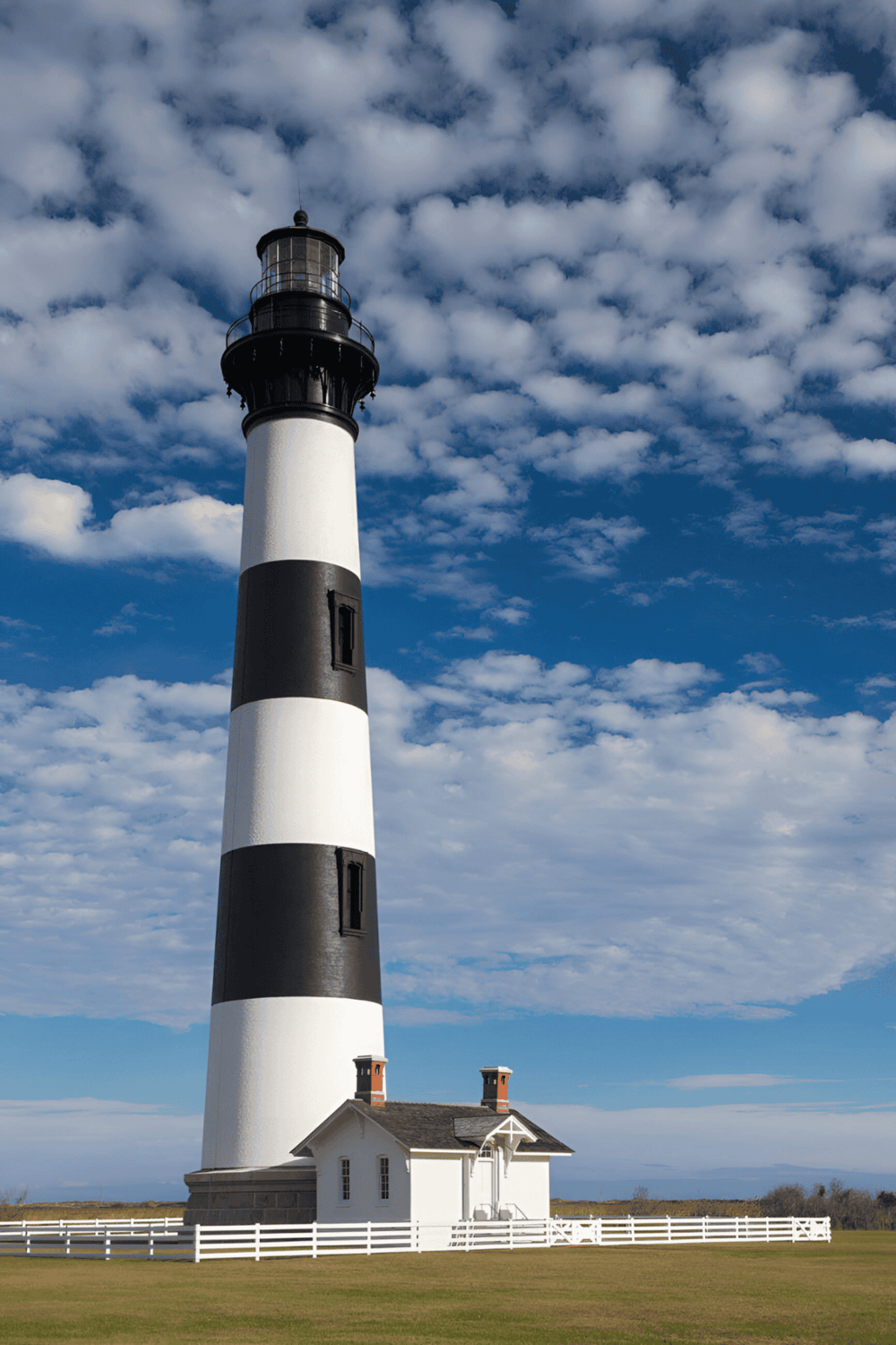 Lighthouse with blue sky and clouds, coastal navigation aid, scenic maritime landmark, iconic lighthouse photography.