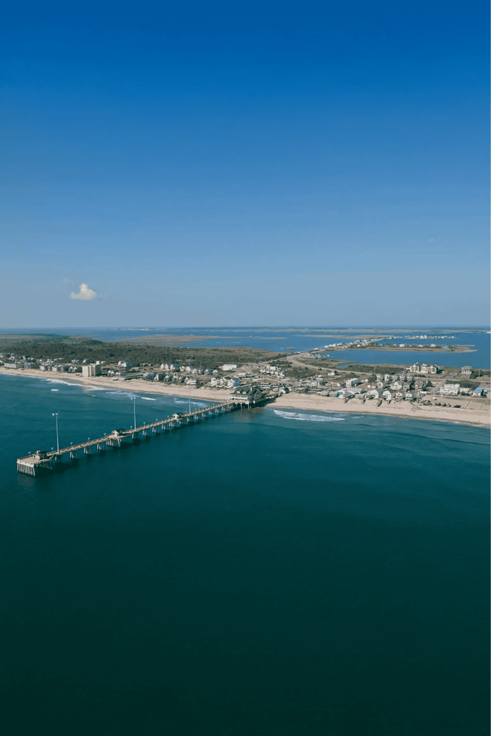 Long beach pier with clear blue sky and coastal town views, perfect for travel and vacation planning.