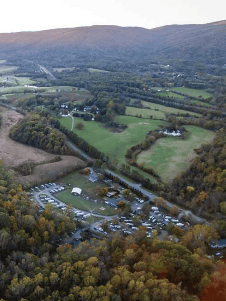 Aerial view of QuestForDirections campus surrounded by lush forests and hilly terrain in a scenic countryside setting.