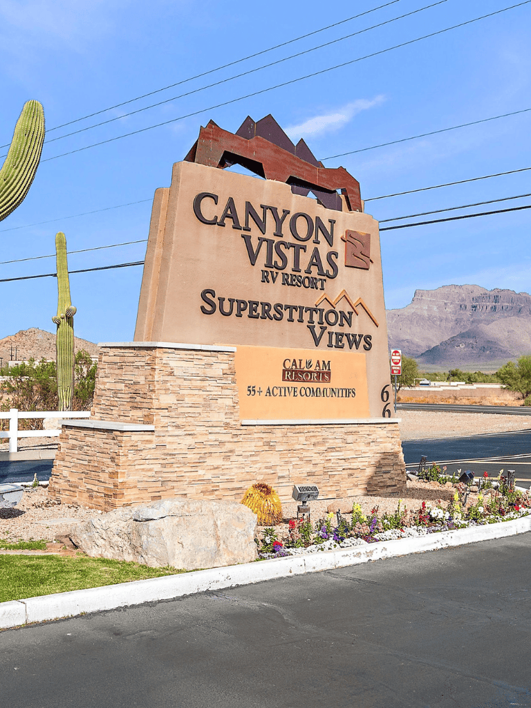 Canyon Vistas RV Resort sign with desert landscape and mountains in background.