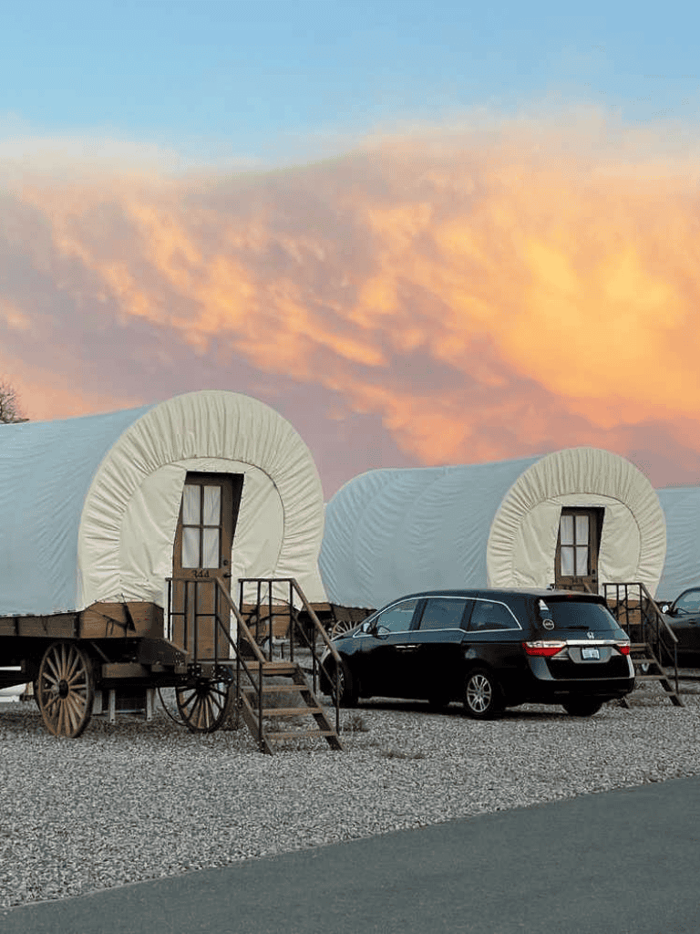 Covered wagons transformed into modern accommodations with cars parked nearby for a unique travel experience.