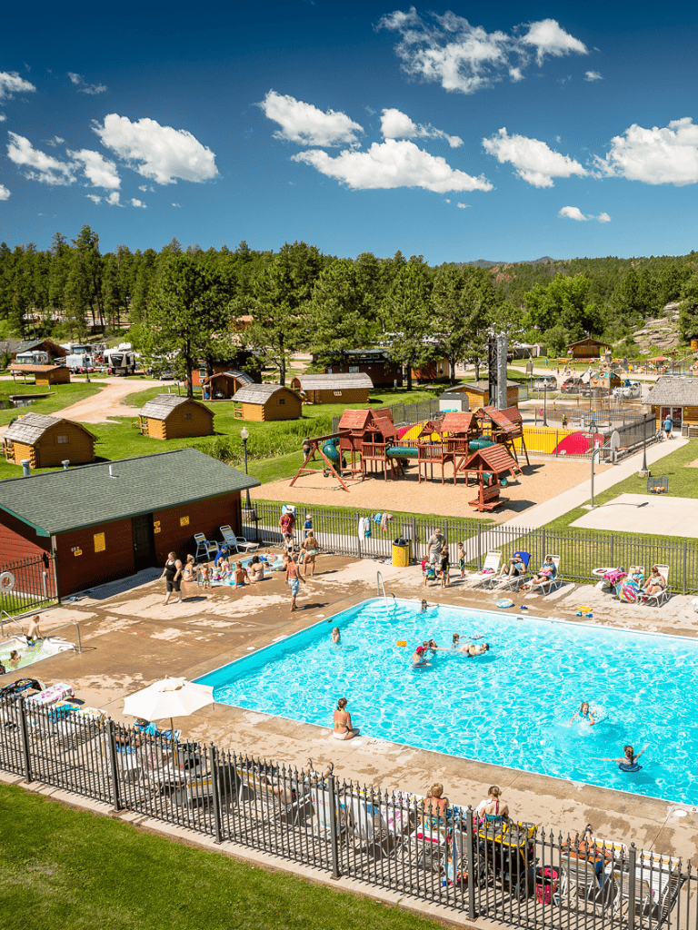 Family-friendly outdoor swimming pool at QuestForDirections resort with playground and scenic mountain views.