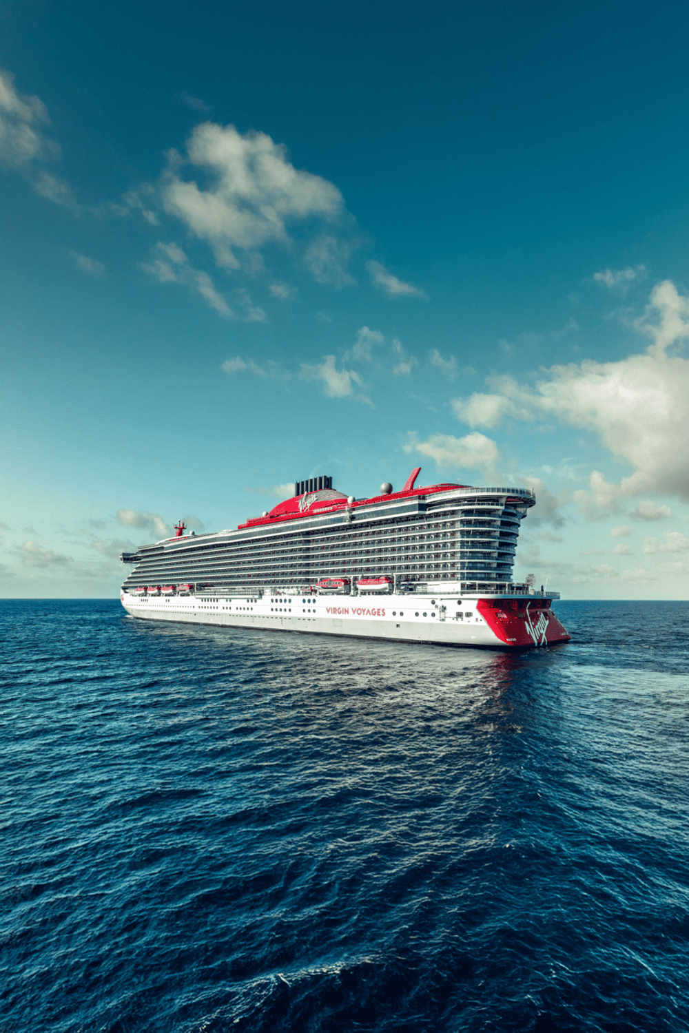 Luxury cruise ship sailing on the ocean with clear blue sky in the background.