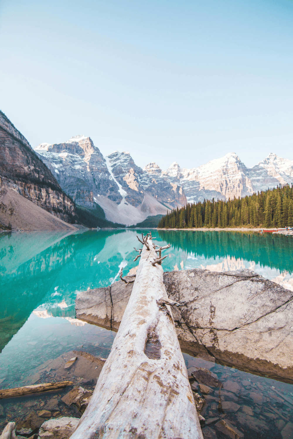 Serene mountain lake scenery with towering snow-capped peaks and lush green trees.