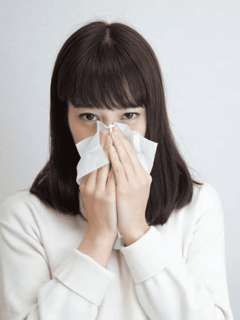 Woman sneezing into tissue, allergy relief and health care concept.