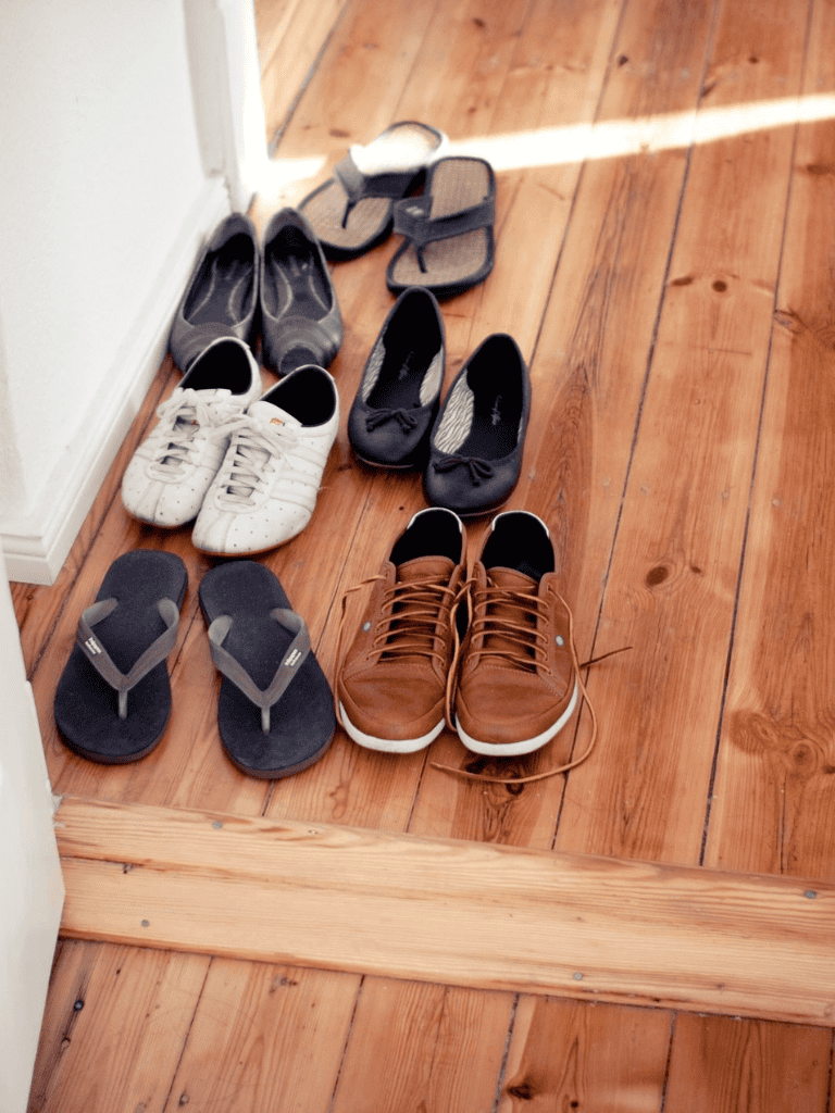 1. Various shoes and slippers on hardwood floor near entryway.