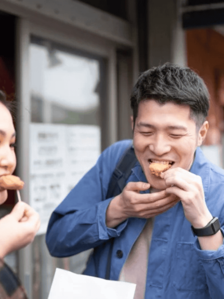 Elderly man enjoying food with a friend outside, showcasing casual dining and social experience.