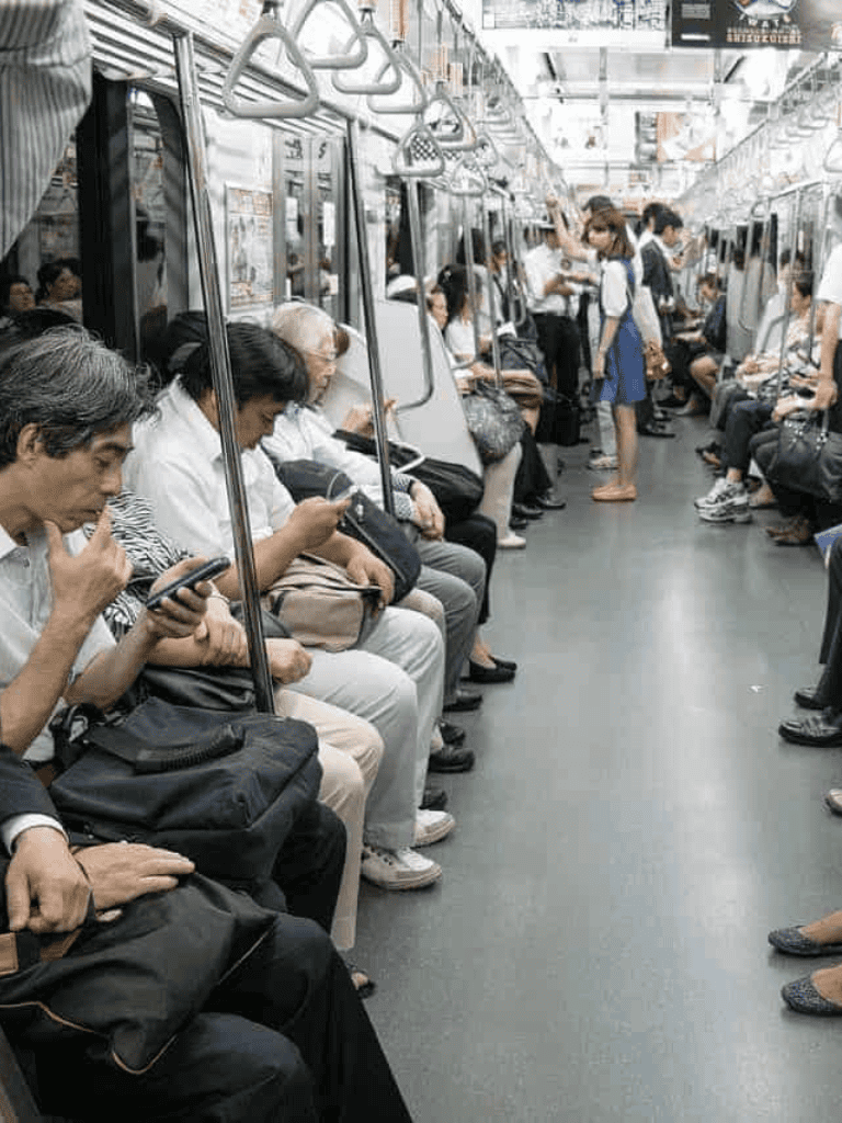 Commuters on subway train using smartphones, public transportation, urban travel, daily commute, city transit, crowded train.