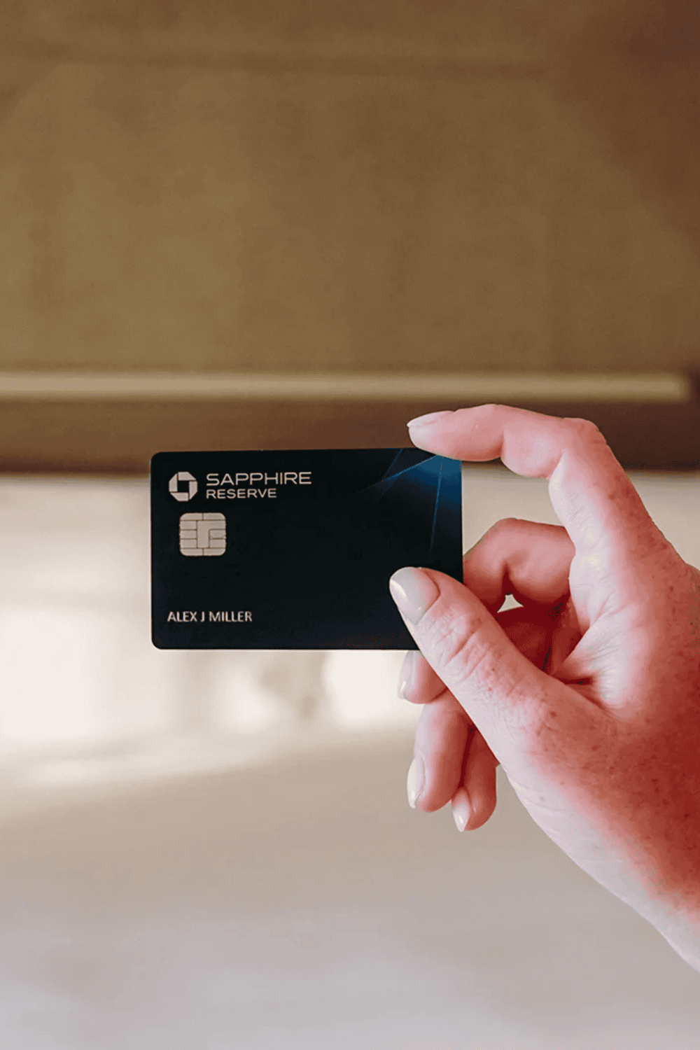 Sapphire Reserve credit card held by hand, airport lounge, premium travel benefits, luxury financial card.