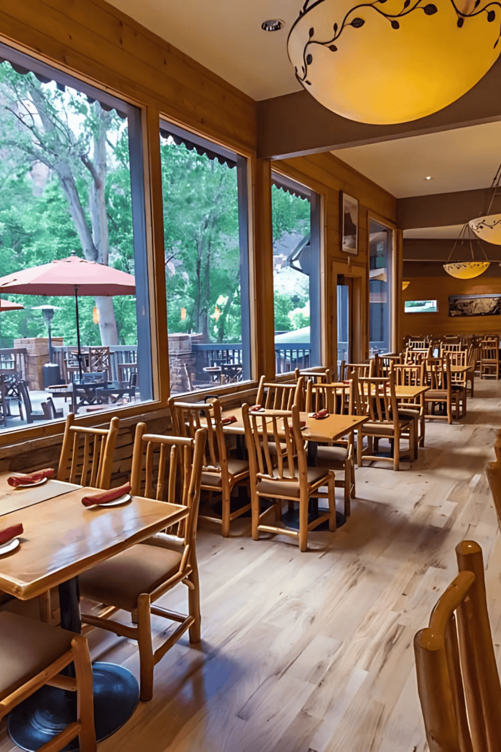 Comfortable wooden restaurant seating with large windows and a view of an outdoor patio.