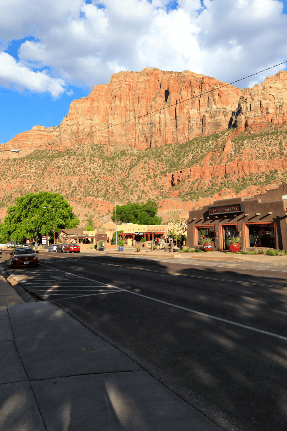 Colorful desert town with red rock mountains and shopfronts, scenic views, and mountain hiking destinations.