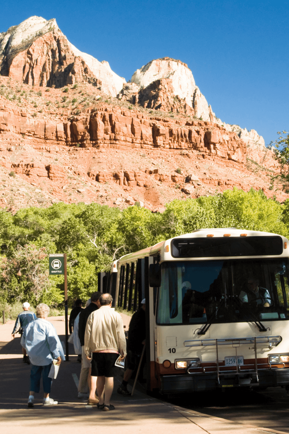Red rocks and mountains at Zion National Park with shuttle bus and visitors.