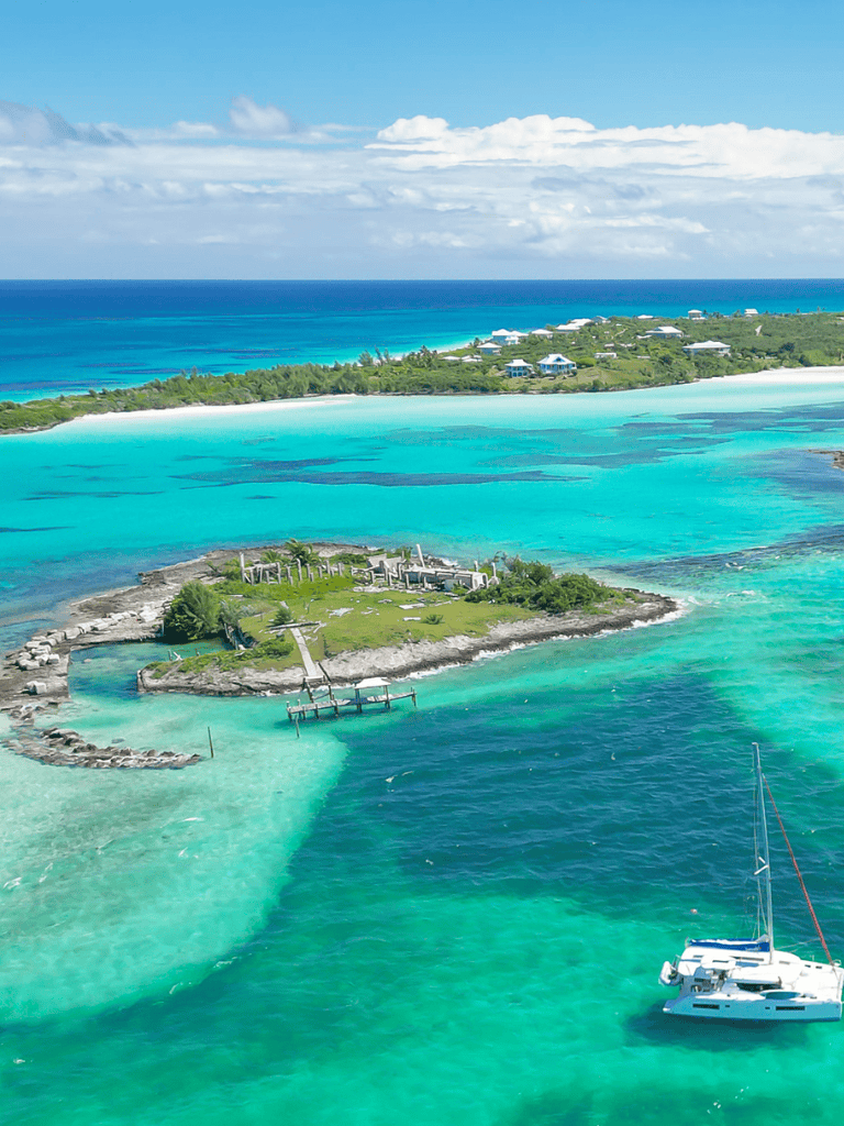 Vibrant turquoise Caribbean waters surrounding a small coastal island with lush greenery and luxury resort homes.