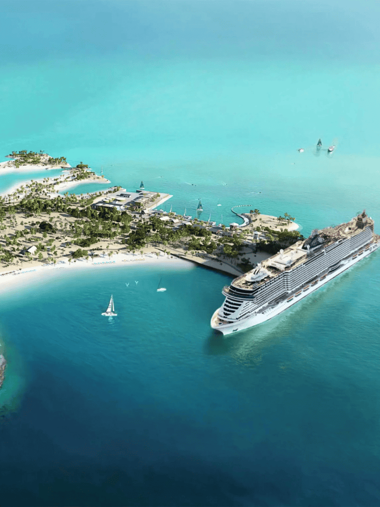 Luxurious cruise ship near tropical island resort with clear blue waters and sailing yachts.
