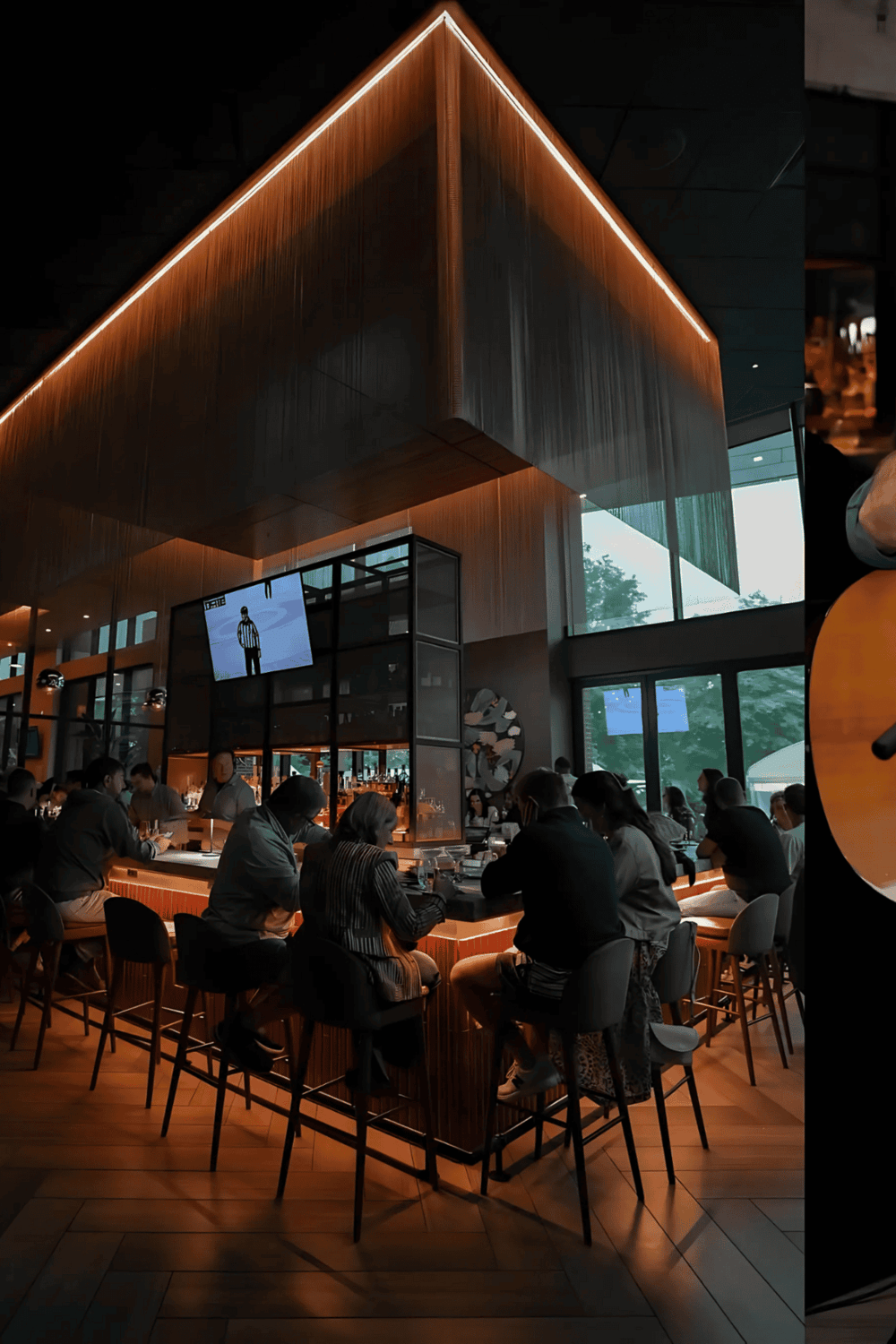 Modern restaurant interior with warm lighting and a lively bar area.