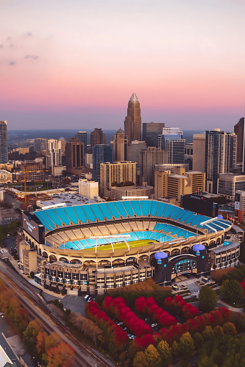 Century-old stadium with vibrant city skyline at sunset, perfect for sports and entertainment events.
