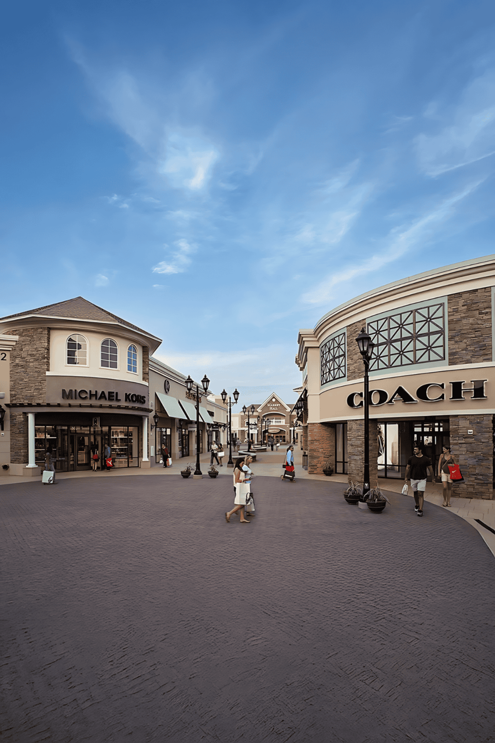 Michael Kors and Coach retail stores in an outdoor shopping mall with people walking and shopping.