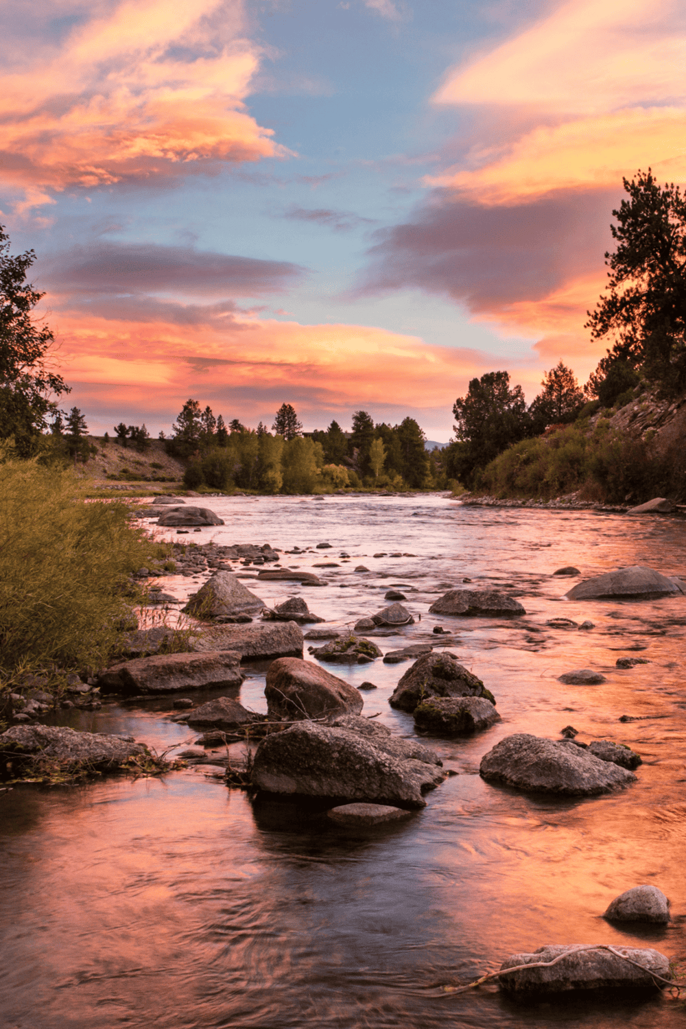 Peaceful river at sunset with colorful sky and scenic natural landscape.
