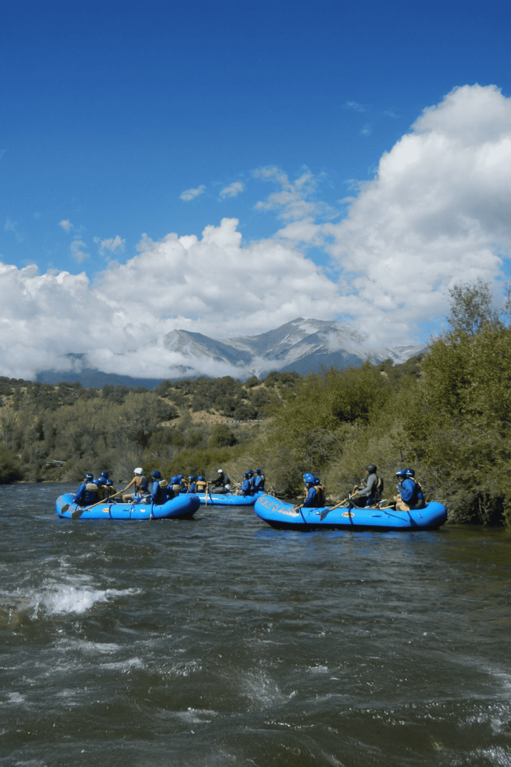 Rafting adventure on scenic mountain river with lush landscape and blue sky.