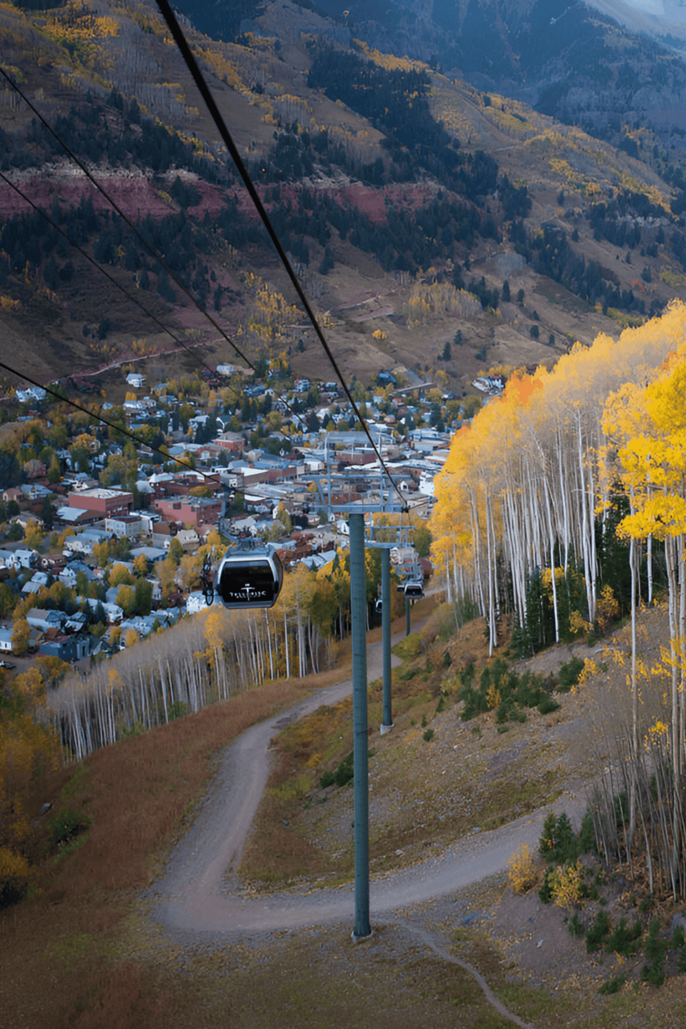 Cable car ride over mountain town with autumn foliage, scenic views, and sustainable transportation options.