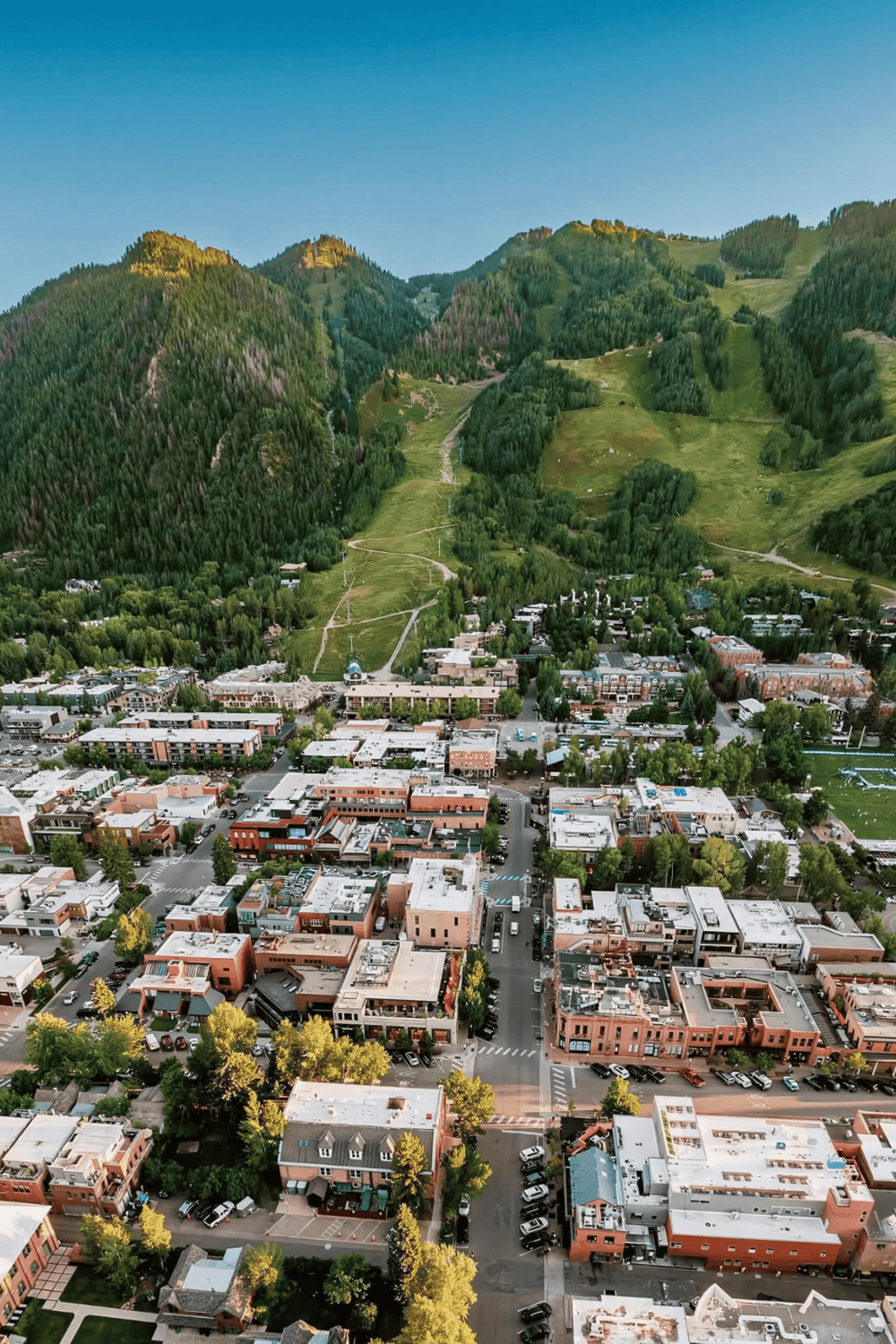 Lush mountain town with vibrant downtown, surrounded by green forested peaks and scenic trails.