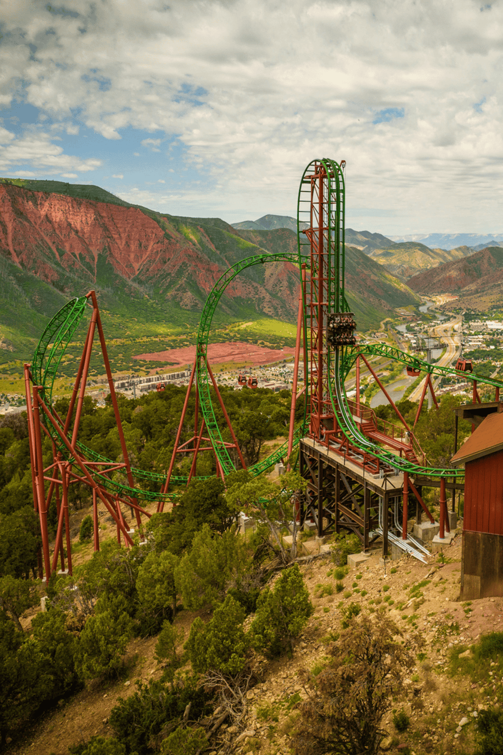 Thrilling roller coaster at QuestForDirections theme park with scenic mountain views in the background.