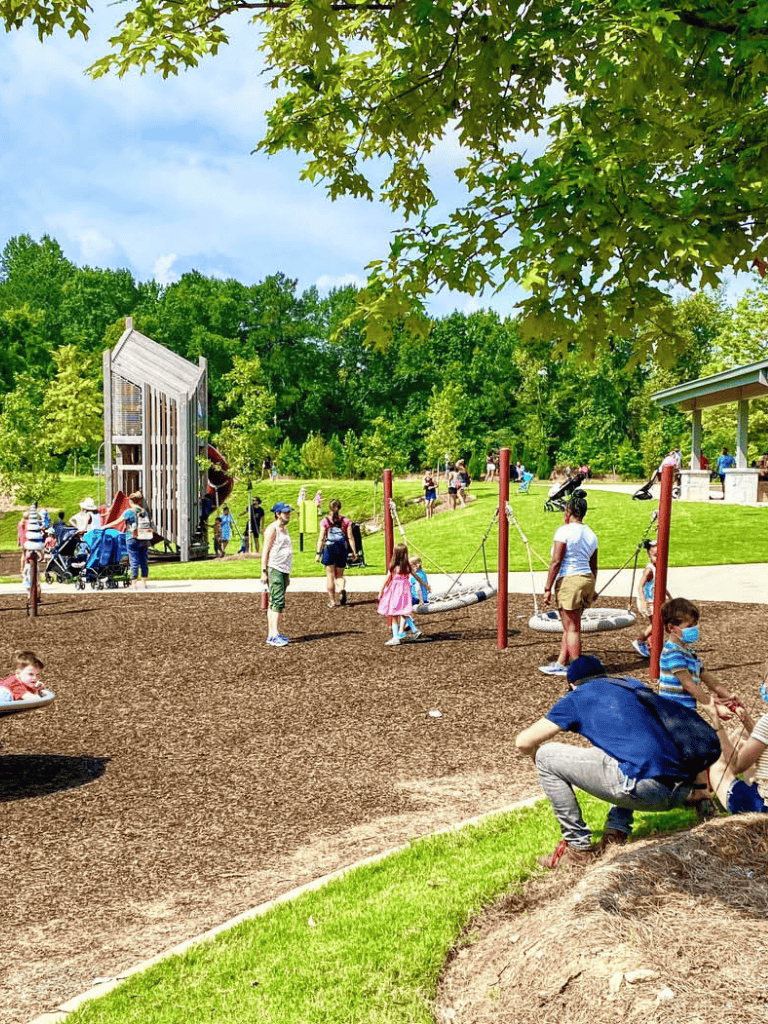 Colorful playground and families enjoying outdoor activities in a lush, green park.